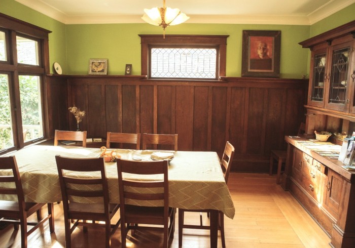 A dining room with a table and chairs, wood paneling, and green walls.