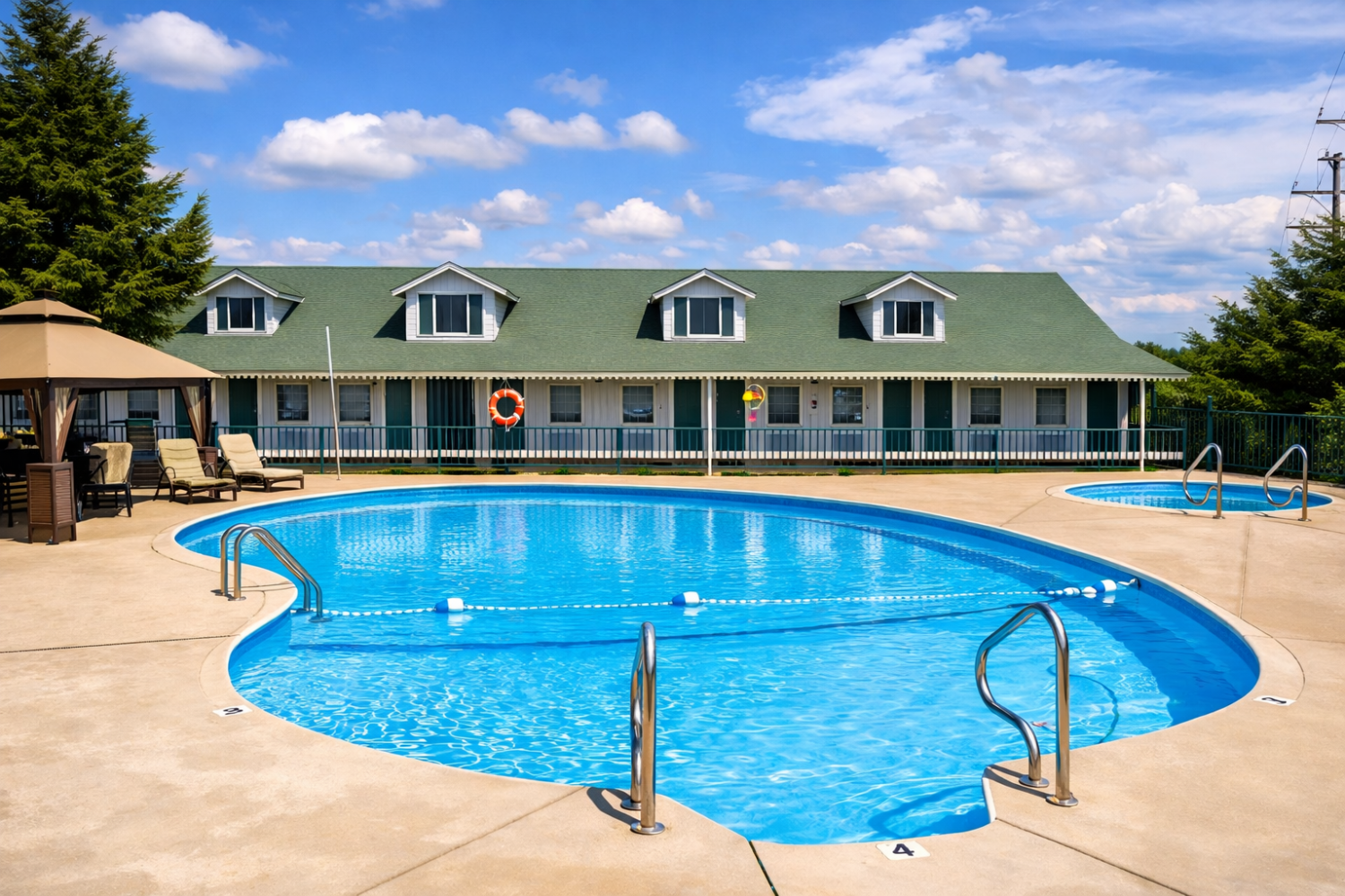 A pool area with a large blue pool, lounge chairs, and a gazebo in front of a building.