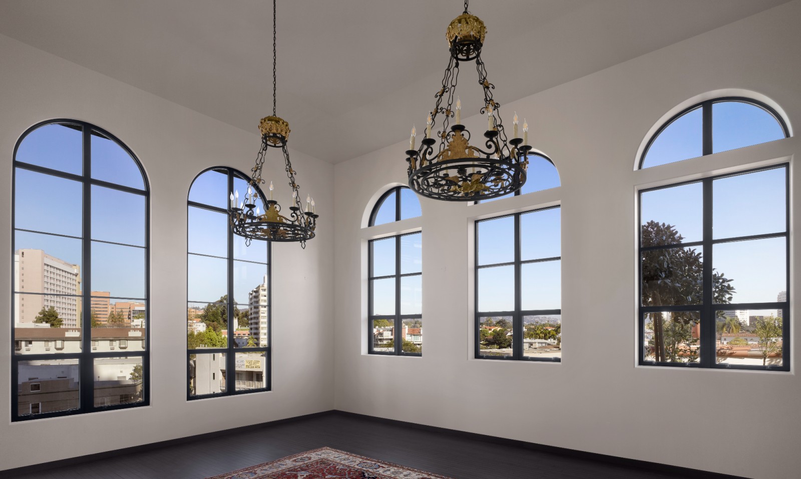 A wide lobby with white walls, black floor, and large windows showing a city view.